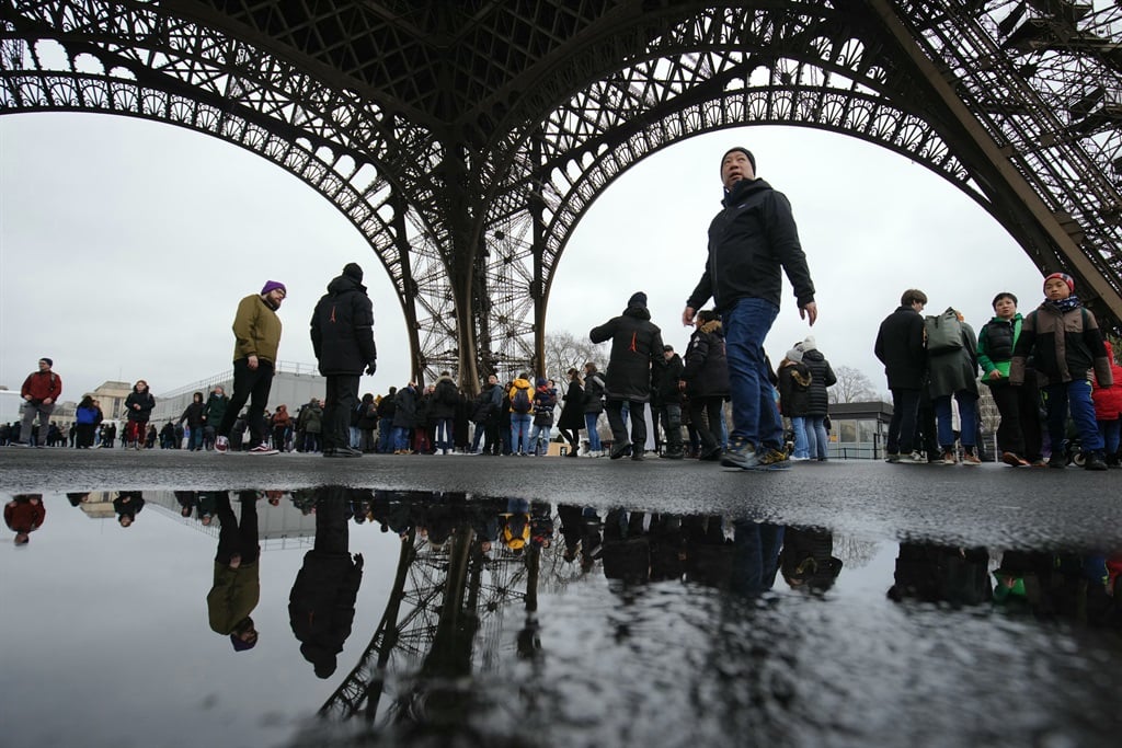 Posjetitelji čekaju u redu ispod Eiffelovog tornja da uđu, na